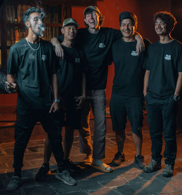 Cinco jóvenes están juntos por la noche, sonriendo y riendo. Uno echa humo. Llevan camisetas de "Film Himal" a juego, lo que crea una sensación de camaradería y amistad.