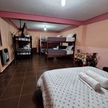 The image depicts a room with bunk beds, a single bed, and a table, featuring a predominantly pink color scheme with brown tile flooring and a white ceiling.