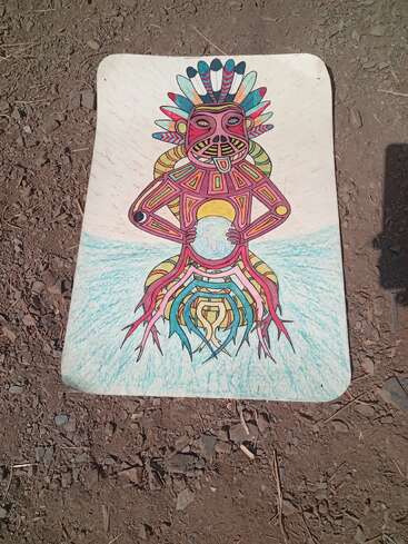 A colorful drawing features a tribal-inspired, geometric figure with vibrant feathers and a crown, holding a blue sphere, set against a simple outdoor background.
