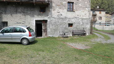 The image shows a house with a large yard and a driveway, featuring a well-manicured lawn and a large tree in the front yard. The house has a gable roof and a covered porch.