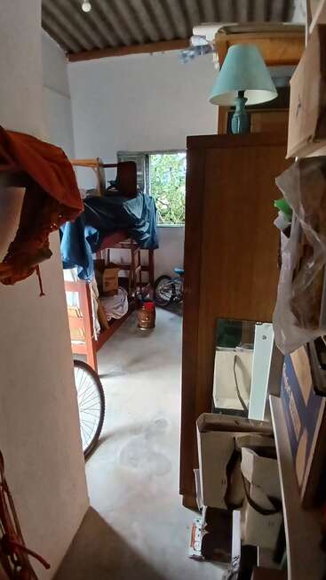 This image shows a cluttered room with bunk beds, a bicycle, boxes, furniture, a turquoise lamp, and a window with greenery visible outside.