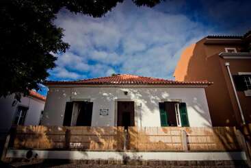 A imagem mostra um edifício branco com um telhado vermelho, com uma placa onde se lê "workaway.info" em letras brancas. O prédio tem uma cerca de madeira na frente.