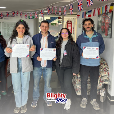 Vier Personen stehen in einem mit britischen Flaggen geschmückten Raum. Drei halten Zertifikate des Blighty Institute Bliss in der Hand und lächeln stolz für ein Gruppenfoto.