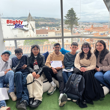 Eine Gruppe von sieben jungen Leuten sitzt lächelnd in einem Raum mit Blick auf die Stadt zusammen. Einer hält ein Zertifikat in der Hand. Das Logo des "Blighty Institute Bliss" erscheint.