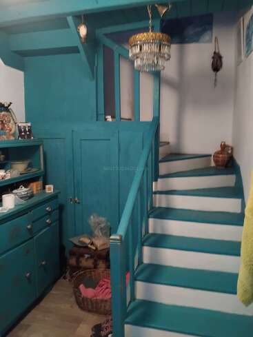 Un intérieur chaleureux et éclectique, avec un escalier, des placards et des boiseries peints en turquoise. Un lustre vintage, des paniers, des céramiques et des objets personnels apportent chaleur et convivialité à l'espace.
