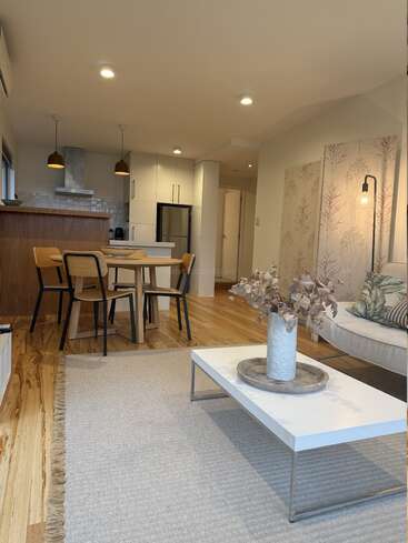 Cette image montre un espace de vie moderne et ouvert avec du parquet, un coin salon confortable, une table à manger, une cuisine, des tons neutres, une décoration élégante et un éclairage tamisé.
