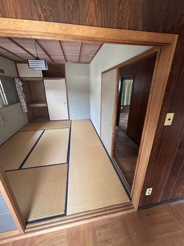 This image shows a traditional Japanese room with tatami mat flooring, sliding shoji doors, wooden ceiling and walls, built-in closet, and natural lighting from windows.