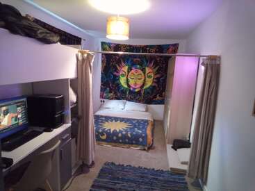 Une chambre à coucher confortable est ornée d'une tapisserie soleil et lune, d'un lit avec une couverture céleste, d'un bureau d'ordinateur, d'une chaise, d'une mezzanine, de rideaux suspendus et d'un plafonnier chaleureux. Un espace accueillant.