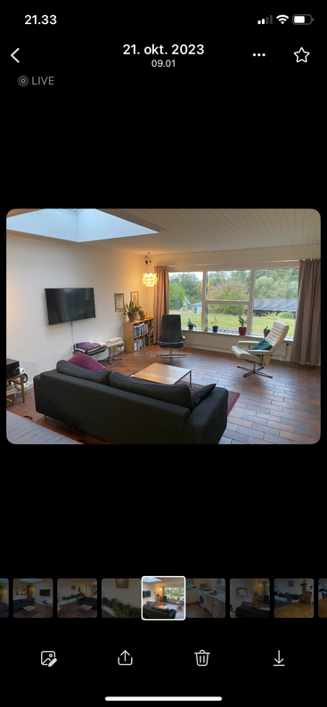 Luminoso salón con gran ventanal, muebles modernos, sillas en blanco y negro, TV, estanterías, plantas, lámpara, suelo de baldosas, acogedoras y acogedoras vistas al exterior.