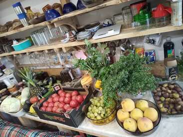 La imagen muestra una despensa de cocina con estantes de madera, en la que se exhibe un surtido de frutas, verduras y utensilios de cocina, con especial atención a la organización y el almacenamiento.