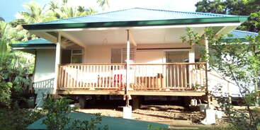 The image depicts a house with a gable roof and a large front yard, featuring a driveway and a garage, with a well-manicured lawn and a large front porch.