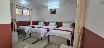 Dieses Zimmer hat drei Einzelbetten mit weißer Bettwäsche und roten Läufern, gestreifte Teppiche, ein Fenster mit Vorhängen und eine schlichte Einrichtung mit Wandkunst.