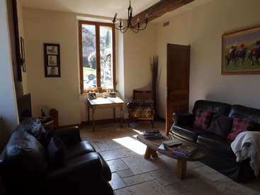 The image depicts a living room with a rustic, country-style aesthetic, featuring a couch, coffee table, and a large window that allows natural light to pour in.