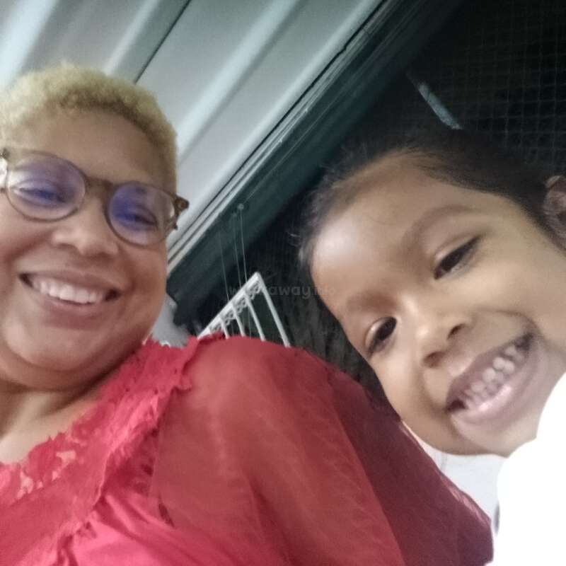 Das Bild zeigt ein Selfie von einem Erwachsenen und einem Kind, die beide lächeln, wobei der Erwachsene links und das Kind rechts rot-weiße Kleidung trägt.