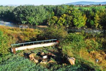 La imagen representa un paisaje sereno atravesado por un río, con una vegetación exuberante y un cielo despejado, que evoca una sensación de paz y tranquilidad. Es probable que la escena se desarrolle en un entorno natural.