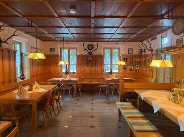 Dieser gemütliche, rustikale Speisesaal ist mit Holzmöbeln, Geweihdekorationen, warmer Beleuchtung und ordentlich gedeckten Tischen ausgestattet und schafft eine einladende, traditionelle Atmosphäre, die perfekt für Versammlungen oder Mahlzeiten ist.