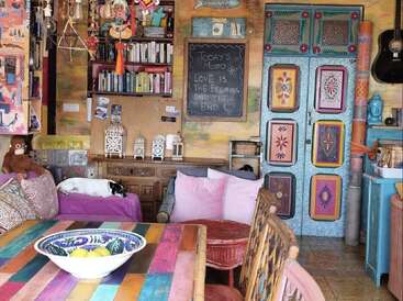 Cette chambre confortable et colorée présente un décor éclectique, un chien endormi, des livres, des oreillers vibrants, un tableau noir avec une devise, des armoires uniques, des œuvres d'art murales et des instruments de musique.