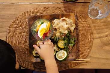 The image shows a table with a plate of food, featuring a bowl of salad and a glass of water, set against a neutral background with no people or animals present.
