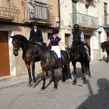 Das Bild zeigt drei Menschen, die auf einer Straße reiten, mit Gebäuden im Hintergrund, die eine einzigartige Mischung aus Reitsport und Stadtlandschaft darstellen.