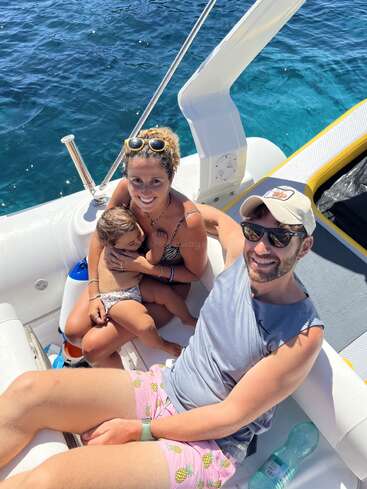 Une famille heureuse est assise ensemble sur un bateau, souriante et profitant d'une journée ensoleillée sur l'eau bleue et limpide, créant de beaux souvenirs lors de leur sortie.