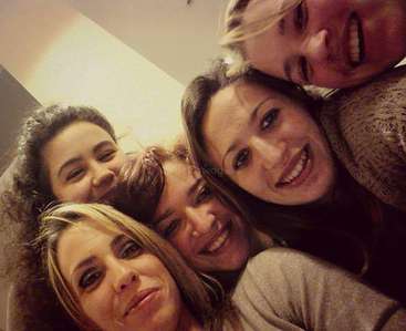 A imagem mostra cinco mulheres posando para uma selfie, com quatro delas amontoadas e uma parcialmente visível no canto superior direito.