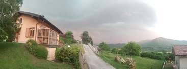 The image depicts a serene scene of a house with a large yard, featuring a well-manicured lawn and a driveway, set against a backdrop of a clear blue sky.