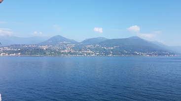 The image depicts a serene lake scene with a prominent mountain range in the background, featuring a body of water and a grassy area, evoking a sense of tranquility and natural beauty.