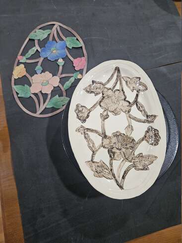The image shows two oval objects with floral patterns: one is a colorful, flat piece, while the other is a white ceramic plate with a black floral design.