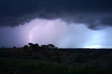 A imagem mostra uma paisagem dramática com um relâmpago à distância, em um céu escuro e ameaçador.