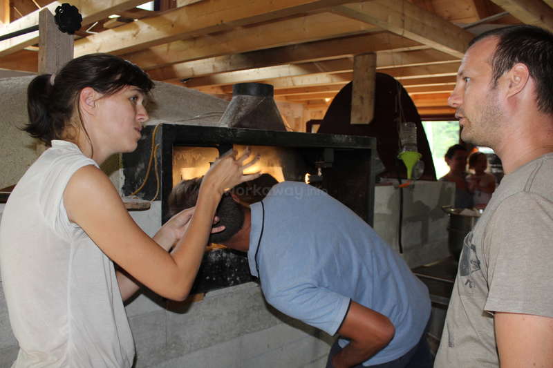 A imagem mostra um grupo de pessoas reunidas em torno de uma mesa, com um grande pedaço de carne no centro, provavelmente para uma refeição ou comemoração. A cena parece ser uma reunião social.