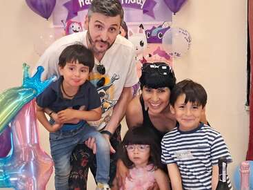 Eine fünfköpfige Familie posiert fröhlich auf einer Geburtstagsparty mit bunten Einhorn-Luftballons, festlicher Dekoration und strahlenden Gesichtern und schafft so gemeinsam einen fröhlichen und unvergesslichen Moment.