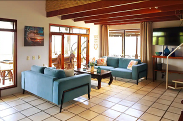 A imagem mostra uma sala espaçosa com teto alto, com uma mesa grande e cadeiras, e bem iluminada, sugerindo um espaço comercial ou público, como um restaurante ou um prédio de escritórios.