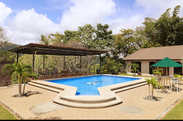 A imagem mostra um ambiente externo sereno, com uma piscina e um pátio, com uma casa grande ao fundo, cercada por árvores e vegetação. A atmosfera é pacífica e convidativa.