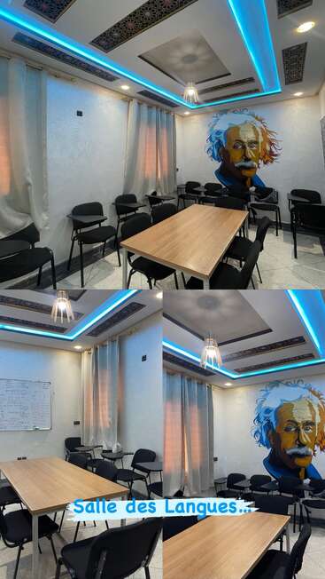 The image shows a modern language classroom with black chairs, wooden tables, a painting of Einstein, blue LED ceiling lights, curtains, and a whiteboard. "Salle des Langues" is written.