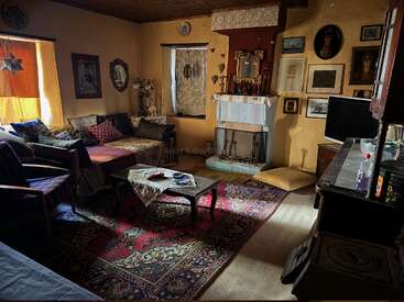 The image depicts a cozy living room with a fireplace, a rug, and a couch, featuring various decorative elements and a warm atmosphere.