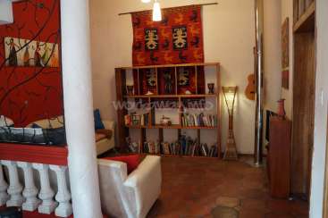 The image depicts a living room with a bookshelf, white couch, and red wall, featuring a mix of modern and traditional decor.