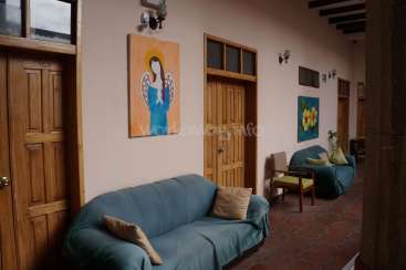 The image depicts a hallway with a blue couch, wooden doors, and a painting of an angel on the wall, evoking a sense of serenity and calmness.