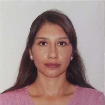 A imagem é uma foto de rosto de uma mulher com longos cabelos escuros, usando um top rosa e brincos de pérola, em um fundo branco.