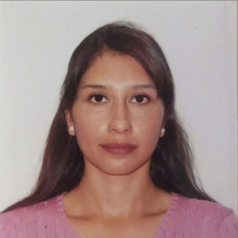 A imagem é uma foto de rosto de uma mulher com longos cabelos escuros, usando um top rosa e brincos de pérola, em um fundo branco.