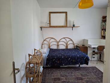 This cozy bedroom has a star-themed bedspread, wooden furniture, a patterned rug, a bookshelf, a desk with a chair, and minimalistic wall decor.
