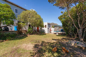 A imagem retrata uma cena serena ao ar livre, com uma casa com um quintal cercado, uma árvore e um corpo d'água, evocando uma sensação de tranquilidade e beleza natural.