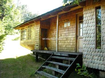 The image depicts a wooden house with a porch and stairs, surrounded by trees and grass, with a watermark reading "workaway.com".