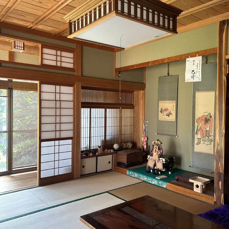 The image depicts a serene Japanese-style room with tatami mats, sliding shoji doors, and a low table, exuding a sense of calm and tranquility.