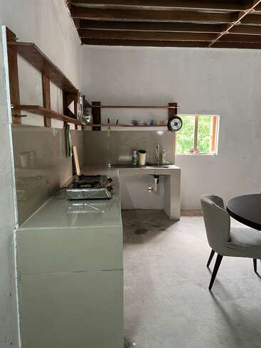 Cette photo montre une cuisine minimaliste avec des plans de travail sobres, un plafond aux poutres apparentes, des étagères ouvertes, une petite cuisinière, une table ronde et une fenêtre laissant entrer la lumière naturelle.