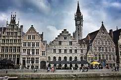 A imagem mostra uma fileira de edifícios ornamentados, de vários andares, com torres e campanários, em um céu nublado.