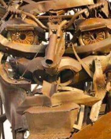 Esta imagen muestra una escultura de rostro humano hecha con varias piezas de metal oxidado y partes de maquinaria, hábilmente dispuestas para formar unos expresivos ojos, nariz y boca.