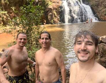 Das Bild ist eine Collage aus sechs Fotos, auf denen Menschen, Bäume und ein Wasserfall zu sehen sind, mit einem rustikalen Gebäude im Bau im Hintergrund.