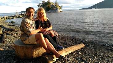 L'image représente une scène sereine d'un couple assis sur une plage, entouré par l'océan, avec une petite île en arrière-plan, évoquant un sentiment de tranquillité et de relaxation.