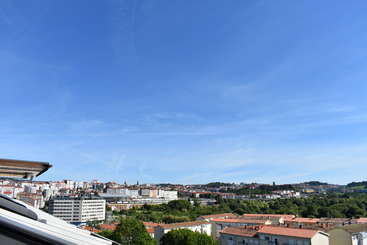L'image représente un paysage urbain avec un bâtiment important, probablement une église, avec un haut clocher et une grande fenêtre, sur fond de plan d'eau et d'herbe.