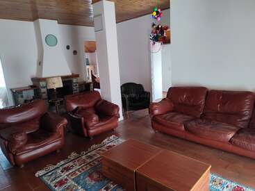 Dieses gemütliche Wohnzimmer ist mit braunen Ledersofas, einem Kamin, einer Holzdecke, einem bunten Teppich, Couchtischen und einer Menge Luftballons ausgestattet, die in der Ecke hängen.